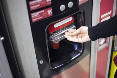 Otomattan sıcak kahve. Bir el, otomatik bir cihazdan elde edilen bir içecekle sıcak bir fincana uzanır. Alışveriş merkezinde kahve. Bir kız, cihazın özel bir bölümünden bir içki alır..