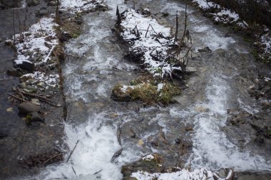 Bir dağ nehri taşların üzerinden akar. Nehir kışın dağlarda. Kayalık bir yamaç boyunca akan bir su. Buzuldan gelen temiz su kayalık bir taban boyunca akar..