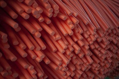 Paralon tüplerinin soyut arkaplanı. Kırmızı paralon silindirlerinin dokusu. İnorganik maddelerden kesilmiş sosislerin teknolojik resmi. Asgari altyapının modern uygulaması.