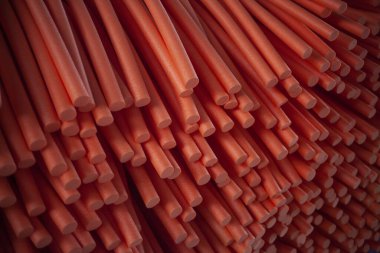 Paralon tüplerinin soyut arkaplanı. Kırmızı paralon silindirlerinin dokusu. İnorganik maddelerden kesilmiş sosislerin teknolojik resmi. Asgari altyapının modern uygulaması.