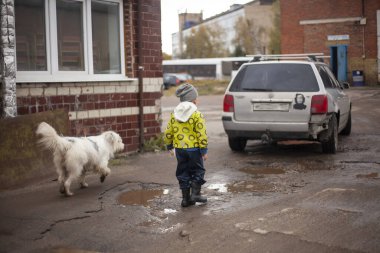 Bir çocuk koşuyor Bir çocuk köpekle su birikintilerinde koşuyor. 