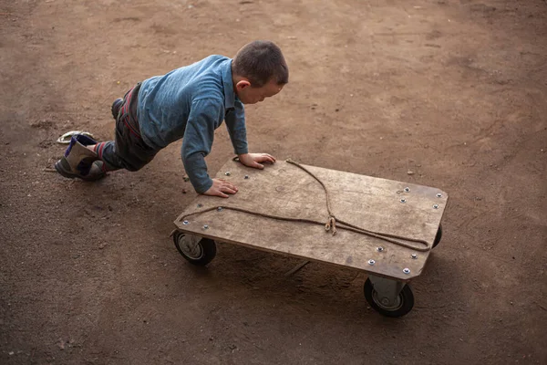 Un niño en un día soleado juega en el garaje con un carro . — Foto de Stock