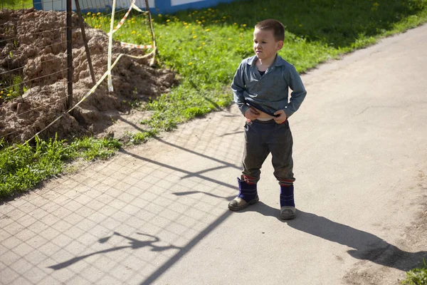 Un niño se para en el verano en la carretera — Foto de Stock