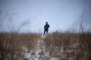 Bir kız kışın tarlada durur.