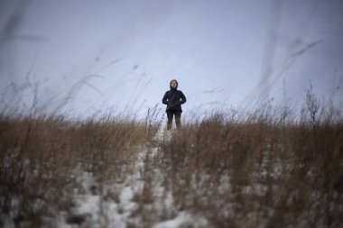 Bir kız kışın tarlada durur.