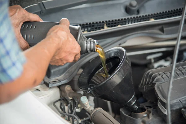 Mechanik pojmania oleju silnika z samochodu do wymiany oleju w sklepie samochodowym — Zdjęcie stockowe