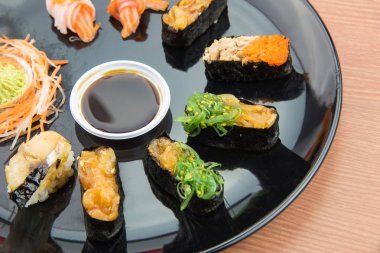Suşi seti ve suşi ruloları ahşap masada servis edilir..