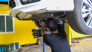 Yağ değişimi için arabadaki motor yağını boşaltan tamirci..