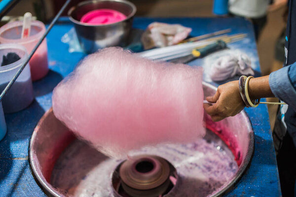 Rolling cotton candy in candy floss machine. Making candyfloss at market street.