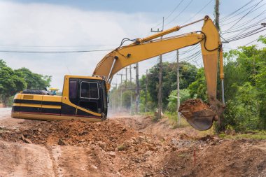 Yol onarımı için sokak asfaltındaki işçi izleme kazıcısı. Caddenin ortasında büyük bir kazıcı kazılmış çukurun yanında duruyor..