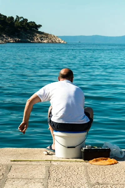 Deniz kıyısındaki iskelede oturan adam