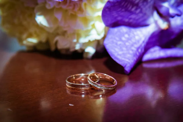 Dvě zlaté snubní prsteny leží na kytice. — Stock fotografie