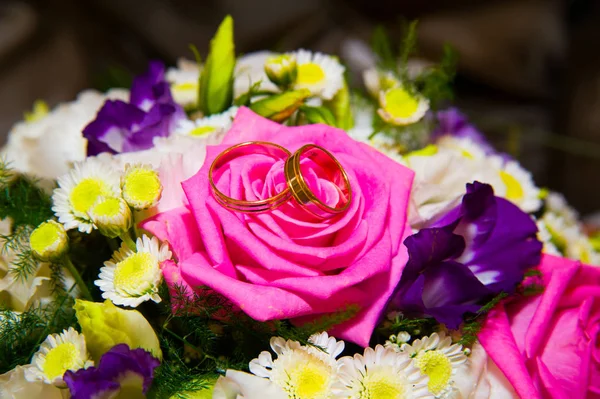 Złote obrączki ślubne, leżącego w pobliżu kwiaty — Zdjęcie stockowe