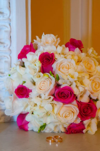 Anillos de bodas de oro que yacen cerca de flores y rosas —  Fotos de Stock