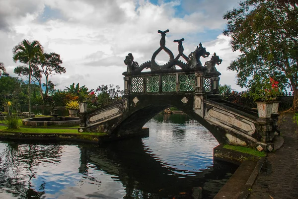 Un puente artificial con cuatro estatuas de dragones con colas retorcidas, parque Tirta Gangga, Karangasem, Bali, Indonesia — Foto de Stock