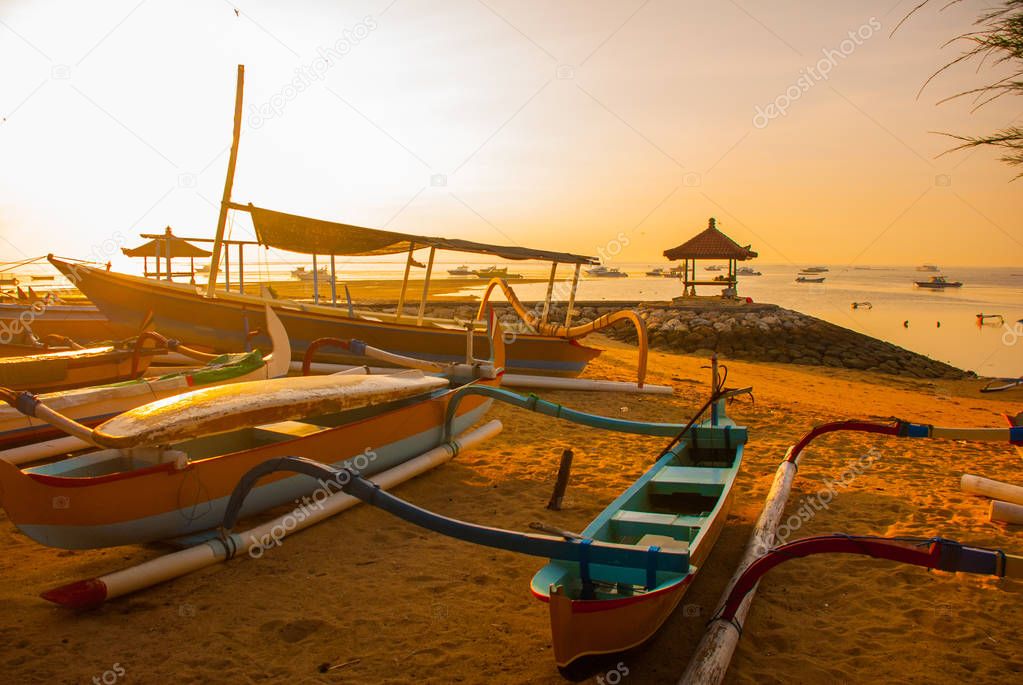 Traditional Balinese boats and pavilion in Sanur beach in the morning at dawn, Bali, Indonesia.