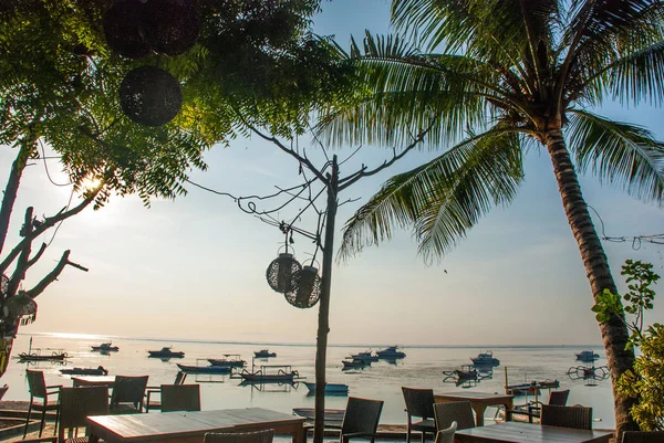 サヌールのカフェで地元の伝統的なボート、明け方のバリ島でヤシの木と美しいビーチ。インドネシア — ストック写真