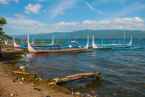 Plusieurs bateaux traditionnels philippins Outrigger ou banca amarrés à une jetée en bois sur la rive du lac Taal, Tagaytay Philippines . — Photo