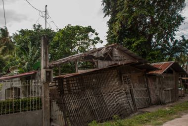 Yerel eski ahşap ev ve büyük yeşil ağaçlar. Filipinler, ada Negros.