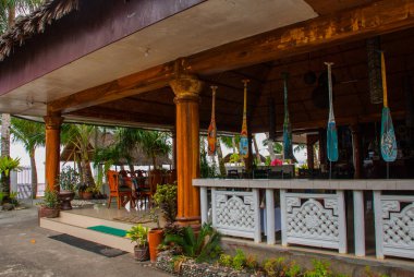 Otel ahşap masa ve sandalyeler zemin palmiye ağaçları ve denizin üzerine. Pandan, Panay, Filipinler.