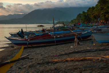 Volkanik kumlu plaj akşam. Dağlar, tekneler ve ağaçlar. Pandan, Panay, Filipinler.