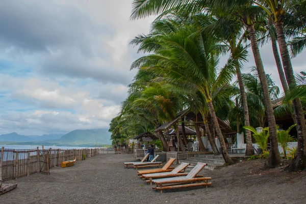 Solsängar och palm träd på stranden mot havet. Pandan, Panay ö, Filippinerna. — Stockfoto