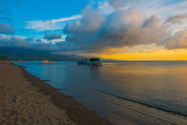 Vulkaniska sandstranden vid solnedgången. Fartyg till sjöss. Pandan, Panay, Filippinerna. — Stockfoto