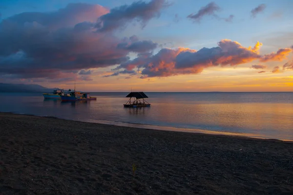 Bellissimo tramonto sulla spiaggia. Silhouette di padiglioni e persone. Pandan, Panay, Filippine . — Foto Stock