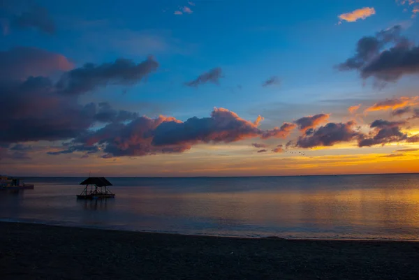 ビーチに沈む夕日。パビリオンと人々 のシルエット。パンダン、パナイ島、フィリピン. — ストック写真