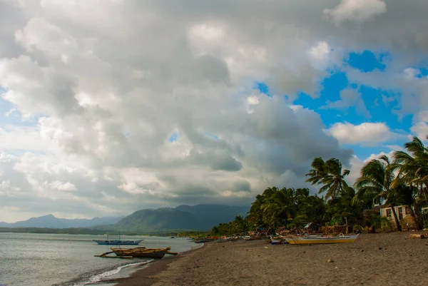 Mare, palme, montagne sulla spiaggia vulcanica. Pandan, isola di Panay, Filippine . — Foto Stock