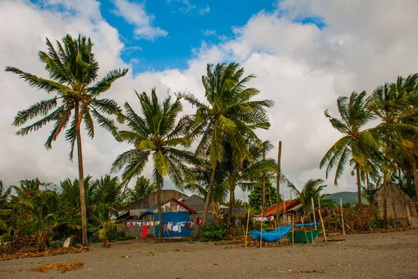 Sea, palm trees, mountains on the volcanic beach. Pandan, Panay island, Philippines.