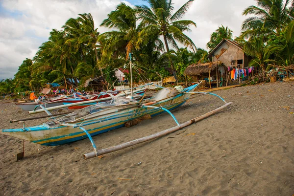 Пальмы и местные лодки на вулканическом пляже. Пандан, остров Панай, Филиппины . — стоковое фото