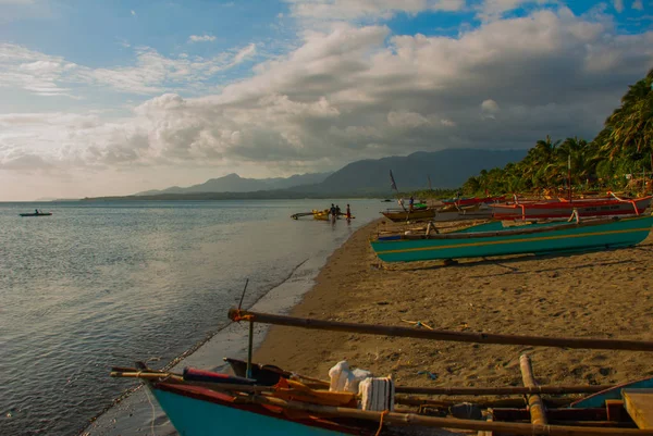 Pescatori e barche sulla spiaggia vulcanica sullo sfondo sono le montagne. Pandan, Panay, Filippine . — Foto Stock