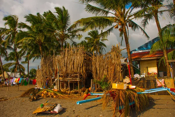 Kleurrijke kleding drogen op een touw op het strand te midden van palmbomen, huis. Pandan, Panay, Filippijnen. — Stockfoto