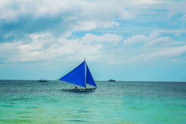 Bulutlar, Boracay Adası, Filipinler bir arka plan üzerinde mavi bir yelken yelkenli tekne