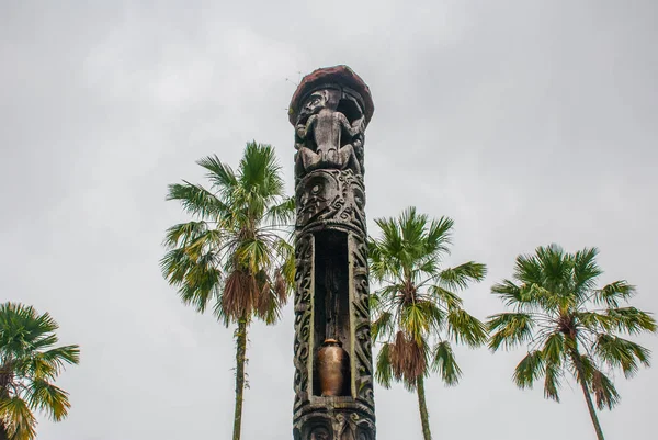 Totem pole against the sky and palm trees Sarawak. Borneo. Malaysia. — Stock Photo, Image