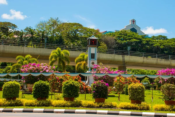 Der uhrturm und blumen, in der ferne der tempel bem canada hill. miri city, borneo, sarawak, malaysia — Stockfoto