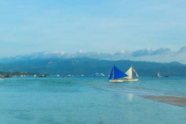 Bulutlar, Boracay Adası, Filipinler bir arka plan üzerinde mavi bir yelken yelkenli tekne