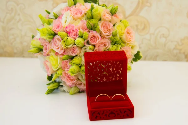 Goldener Ehering, eine rote Schachtel und ein Blumenstrauß der Braut — Stockfoto