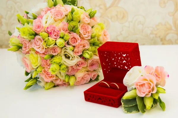 Gouden trouwring, rode doos, bruidegom corsages en een boeket van bloemen bruid — Stockfoto