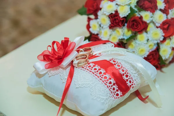 Two gold wedding rings lie and a bouquet of red roses. — Stock Photo, Image