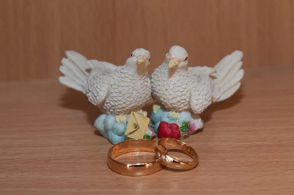 Snubní zlaté prsteny a socha s holuby. — Stock fotografie