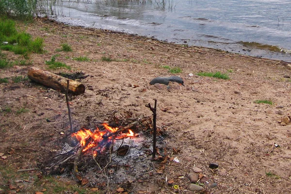 Paysage au bord de l'eau par temps nuageux, sur la Banque allumé un feu de joie. Russie . — Photo