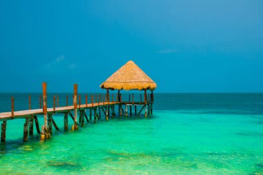 İskele ve plajda ahşap çardak. İskelesi ile tropikal manzara: Deniz, kum, kaya, dalgalar, turkuaz su. Meksika, Cancun