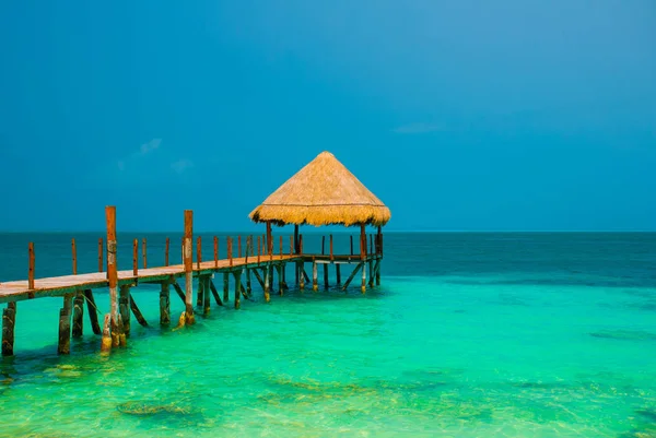 Molo i drewniana altana na plaży. Tropikalny krajobraz z molo: morze, piasek, skały, fale, turkusowa woda. Meksyk, Cancun — Zdjęcie stockowe