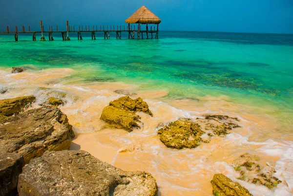 Pier en de houten prieel aan het strand. Tropische landschap met steiger: zee, zand, stenen, golven, turkoois water. Mexico, Cancún — Stockfoto