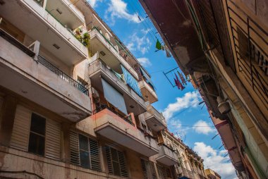 Aşağıdan yukarıya görünümü: her zamanki paneli şirketten giyim ve kurutma, mavi gökyüzü bulutlu asılı halatlar balkonda. Havana. Küba