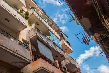 Aşağıdan yukarıya görünümü: her zamanki paneli şirketten giyim ve kurutma, mavi gökyüzü bulutlu asılı halatlar balkonda. Havana. Küba