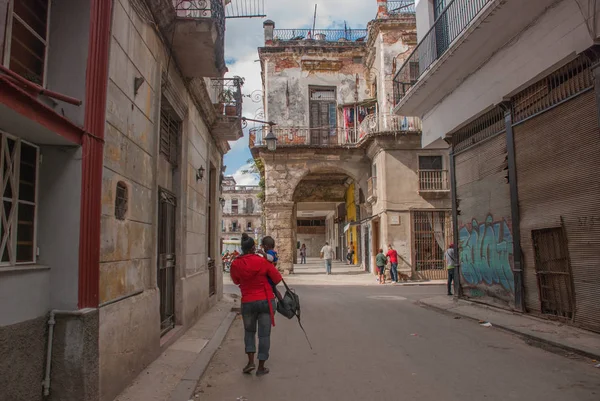 Женщина сзади в красной куртке с ребёнком, идущим по улице. Гавана. Куба — стоковое фото