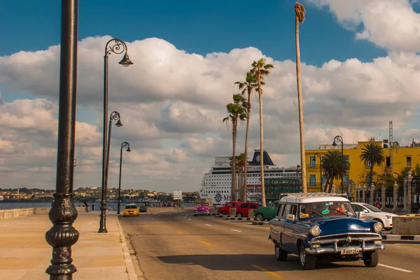 Uitzicht vanaf de Malecon waterkant. Enorme schip in de haven van Havana. Retro blauwe auto rijdt op de weg. Cuba. — Stockfoto